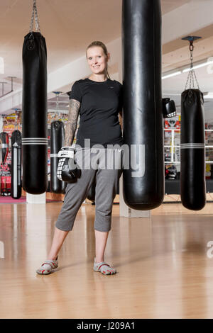 Junge Frau, tätowiert, Boxen an einem Sandsack in einem Box-Studio, Bayern, Deutschland Stockfoto