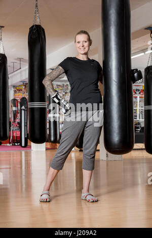 Junge Frau, tätowiert, Boxen an einem Sandsack in einem Box-Studio, Bayern, Deutschland Stockfoto