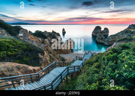 Holzsteg Fußweg zum schönen Strand Praia Camilo auf Region Küste der Algarve, Portugal bei Sonnenaufgang Stockfoto