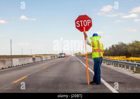 Straßenbau auf der Autobahn, hält Arbeiter ein Stop-Schild auf den Verkehr zu kontrollieren Stockfoto