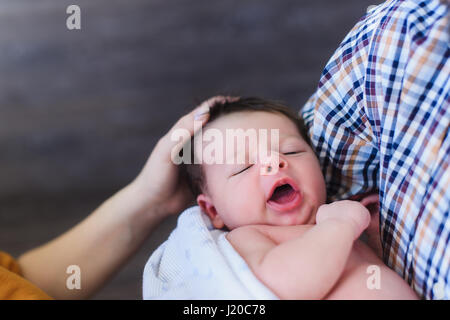 Neugeborenes in den Händen seines Vaters. Mama sanft streichelte den Kopf des Babys. Stockfoto