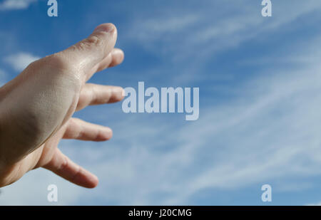 Hand ausstrecken gegen blauen Himmel Stockfoto