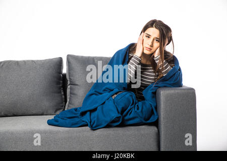 Kranke Frau mit Kopfschmerzen sitzen unter der Decke Stockfoto