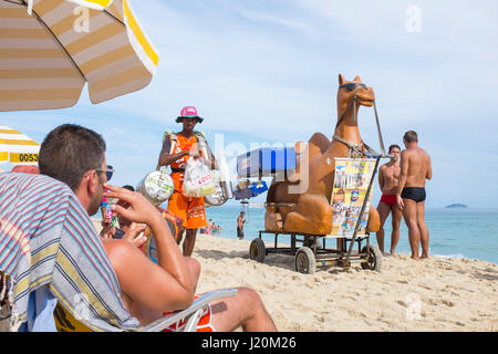 RIO DE JANEIRO - 22. Februar 2017: Strandverkäufer mit Snacks aus einem Warenkorb in Form von einem Kamel Stop für Kunden am Strand von Ipanema. Stockfoto