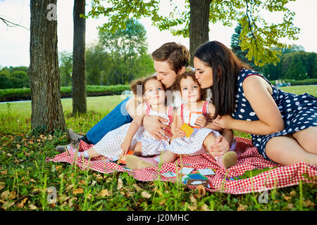Happy Family im Park Sommer, Herbst. Eltern und zwei Töchtern sitzen, spielen. Stockfoto