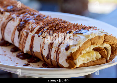 Biskuitrolle Kuchen Roll Rollen Scheiben süße Sahne auf ein Schneidebrett Stockfoto