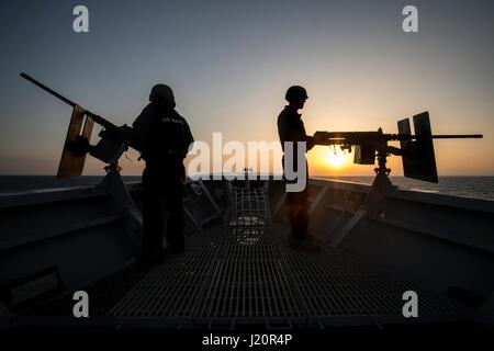 US Navy Matrosen sind von der untergehenden Sonne Silhouette, wie sie.50 Kaliber Maschinengewehre an Bord auf dem Bogen der USN Ticonderoga-Klasse geführte Flugkörper Kreuzer USS Vella Gulf 7. Juli 2014 in das Ägäische Meer Mann.   (Foto von Edward Guttierrez III EURO1 Navy über Planetpix) Stockfoto