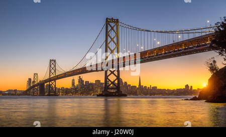 Klassische Panoramablick auf die Skyline von San Francisco mit berühmten Oakland Bay Bridge beleuchtet im schönen goldenen Abendlicht bei Sonnenuntergang im Sommer, San Stockfoto