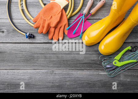 Gummistiefel und Gartengeräte. Stilleben auf Holzbrettern. Stockfoto