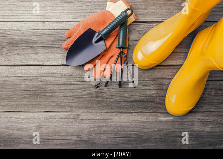 Gummistiefel und Gartengeräte. Stilleben auf Holzbrettern. Stockfoto