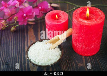 Meer-Badesalz, Kerzen und Blumen auf einem hölzernen Hintergrund. Das Konzept der Entspannung und Wellness. Stockfoto