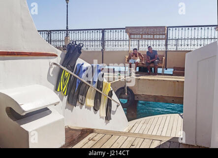 Egypt.Hurgada-Oktober, 6,2016. Zwei arabische jungen Erwachsenen männlichen Männer sitzen auf einer Bank auf dem Dock zeigt ein Daumen hoch Zeichen. Blick von der Yacht mit Flossen fo Stockfoto