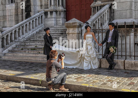 Strahlende asiatische Braut & Bräutigam posieren für Fotografen unter Hochzeit Porträt in Paris Stockfoto