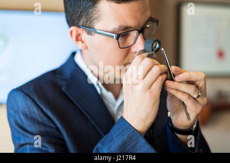 Juwelier Diamanten gründlich durch Lupe untersuchen Stockfoto