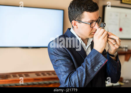 Juwelier Diamanten gründlich durch Lupe untersuchen Stockfoto