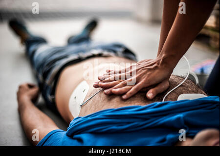 ein Mädchen hilft einen Kerl nach dem Herzinfarkt mit Reanimation Stockfoto