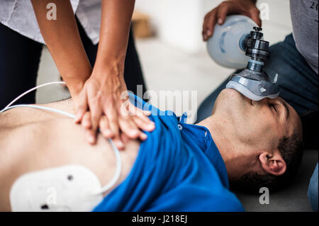 ein Mädchen hilft einen Kerl nach dem Herzinfarkt mit Reanimation Stockfoto