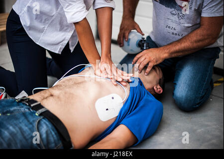 ein Mädchen hilft einen Kerl nach dem Herzinfarkt mit Reanimation Stockfoto