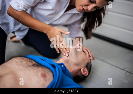 ein Mädchen hilft einen Kerl nach dem Herzinfarkt mit Reanimation Stockfoto