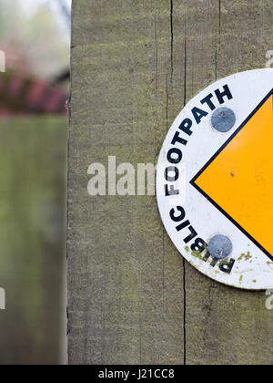 Die Hälfte der ein Schild an einem Holzpfosten sagen öffentlichen Fußweg mit Halbkreis und gelbe Pfeilspitze führt nach links, um den Weg in Großbritannien im Frühjahr Stockfoto