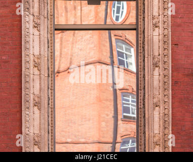 Reflektion von einem alten Backsteingebäude in London in einem Fenster mit kunstvollen Formen, London, England, Grossbritannien Stockfoto