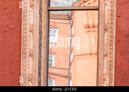 Reflektion von einem alten Backsteingebäude in London in einem Fenster mit kunstvollen Formen, London, England, Grossbritannien Stockfoto