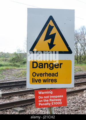 Eine Eisenbahn Sicherheit Zeichen sagen Gefahr Overhead Live Wire Warnung tun nicht Hausfriedensbruch auf der Bahn Strafe £1000 in schwarz, gelb, rot und weiß mit Trac Stockfoto