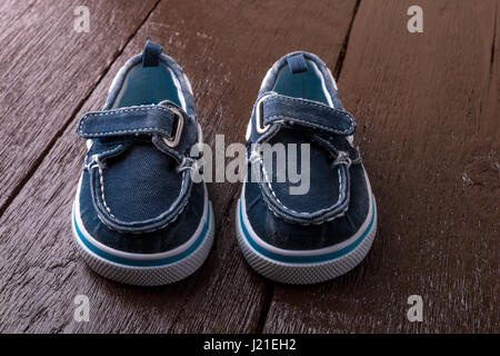 Blaue Bootsschuhe auf braunem Hintergrund aus Holz. Jungen Schuhe. Stockfoto