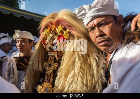 Kesiman, Denpasar, Bali, Indonesien. 23. April 2017. Balinesische Mann hilft Rangda die Dämon-Königin der Hexen während der Trance bei Messer-Ritual der Sakral an der Pengerebongan-Zeremonie selbst. Dieses Ritual findet alle 210 Tage auf dem hinduistischen Balinesen Saka-Kalender die Gebete und Opfergaben, eine Parade von mythologischen Figuren, Männer und Frauen in Trance mit einigen Männern, die versuchen, ihre Haut mit einem traditionellen Keris (Messer) durchbohren mit sich bringt, zum Glück niemand wird verletzt bei dieser unglaublichen balinesische Zeremonie in Pura Petilan Tempel, Denpasar, Indonesien. Bildnachweis: Antony Ratcliffe/Alamy Li Stockfoto