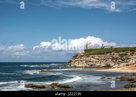 Capo Mannu Cliffs in Sardinien, Italien gegen türkisblauen Meer oder Ozean mit blauen Himmel und geschwollenen Wolken. Alten Wachturm im Hintergrund. Stockfoto