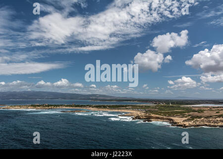 Capo Mannu Cliffs und Strand gegen blaue Meer oder Ozean mit blauen Himmel und Cumulus-Wolken. Schuss in Capo Mannu, Mesa Longa Strand, Sardinien, Italien. Stockfoto