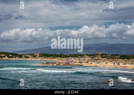 Mesa Longa Strand von Capo Mannu, Sardinien, Italien mit blauen Meer oder Ozean, blauer Himmel und geschwollenen Wolken überfüllt.  Es gibt viele bunte Sonnenschirme/Sonnenschirm. Stockfoto