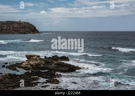 Capo Mannu Cliffs in Mesa Longa Strand, Sardinien, Italien gegen blaues Meer und blauer Himmel und Wolken. Alten Wachturm kann im Hintergrund zu sehen. Stockfoto