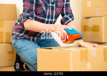 Junges Mädchen bewegt sich in eine neue Wohnung, umgeben mit Kartons, Verpackung und taping Boxen. asiatische chinesische Modell Mischlinge Stockfoto