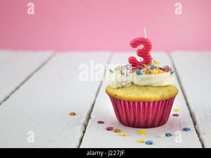 Alles Gute zum Geburtstag Tasse Kuchen mit Stern besprengt und Nummer 3 Rosa Kerze auf weißen Tisch mit rosa Hintergrund - Geburtstag Feier Hintergrund für Mädchen Stockfoto
