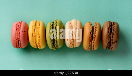 Süße bunte Macarons in Folge auf Türkis Hintergrund Stockfoto