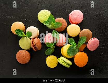 Süße bunte Macarons auf schwarzen steinigen Tisch Stockfoto