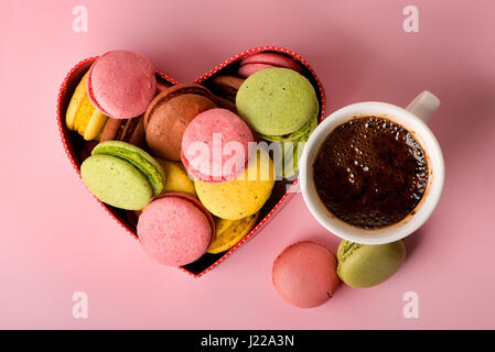 Macarons in Geschenkbox mit einer Tasse Kaffee auf rosa Hintergrund Stockfoto