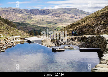 Wehr auf Afon Llançà Fluss kleine micro Hydro-elektrischen Regelung neben der Watkin Pfad mit Wanderern in Snowdonia National Park. Cwm Llançà Wales UK Stockfoto