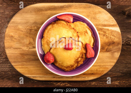 Ein Foto von hausgemachte Pfannkuchen mit frischen Erdbeeren und Himbeeren, geschossen von oben auf rustikalen Holz Texturen mit Textfreiraum Stockfoto