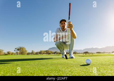 Pro Golf-Spieler mit dem Ziel geschossen mit Club auf Kurs. Golfer, die hocken und Studie der grünen vor Aufnahme Stockfoto