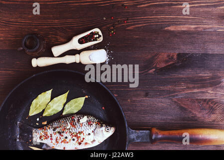 Flussfisch Karpfen mit Gewürzen in einer schwarzen gusseisernen Pfanne, Ansicht von oben Stockfoto