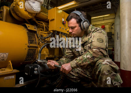 Ein Ingenieur der US Army Reserve von der 949th Transportation Company posiert im Maschinenraum an Bord eines Logistics Support-Schiffes in Baltimore, Maryland, und demonstriert seine Aufgaben im Zusammenhang mit Wasserfahrzeugbetrieb, Frachtumschlag und Maschinenbau. Stockfoto