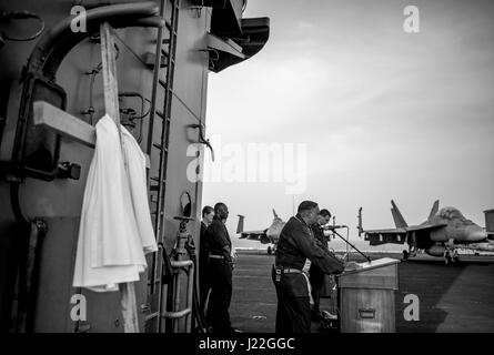 170416-N-AF077-096 BAHRAIN (16. April 2017) Commander John Logan, hielt Navy Kaplan an Bord des Flugzeugträgers USS George H.W. Bush (CVN-77) (GHWB), liest ein Gebet beim Sonnenaufgang Ostern Service auf dem Flugdeck. George h.w. Bush Carrier Strike Group in den USA bereitgestellt wird 5. Flotte Bereich der Maßnahmen zur Erhöhung der Sicherheit im Seeverkehr Operationen, Verbündete und Partner zu beruhigen, und bewahren die Freiheit der Schifffahrt eine den freien Fluss des Handels in der Region. (Foto: U.S. Navy Mass Communication Specialist 1. Klasse Sean Hurt/freigegeben) Stockfoto