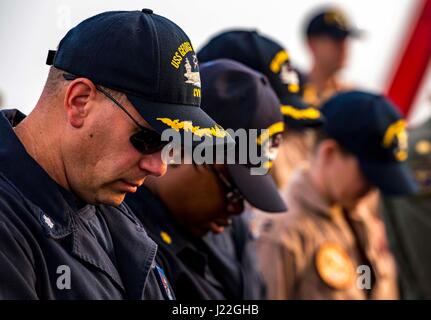 170416-N-OX430-040 BAHRAIN (16. April 2017) Commander Robert Lutz Bögen seinen Kopf während Gebet Ostergottesdienst ein Sonnenaufgang auf dem Flugdeck des Flugzeugträgers USS George H.W. Bush (CVN-77) (GHWB hielt). GHWB in den USA bereitgestellt wird 5. Flotte Bereich der Maßnahmen zur Erhöhung der Sicherheit im Seeverkehr Operationen, Verbündete und Partner zu beruhigen, und die Freiheit der Schifffahrt und den freien Fluss des Handels in der Region zu erhalten. (Foto: U.S. Navy Mass Communication Specialist 3. Klasse Daniel Gaither/freigegeben) Stockfoto