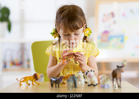 Kind spielt mit tierischen Spielzeug am Tisch im Kindergarten oder zu Hause Stockfoto
