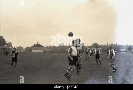 1950er Jahre, ein Bewunderer Fußballspiel, zwei Fußballer in langen Baggy Shorts und knöchelhohe Stiefel aus Leder für den Ball in der Luft, England konkurrieren. UK. Stockfoto