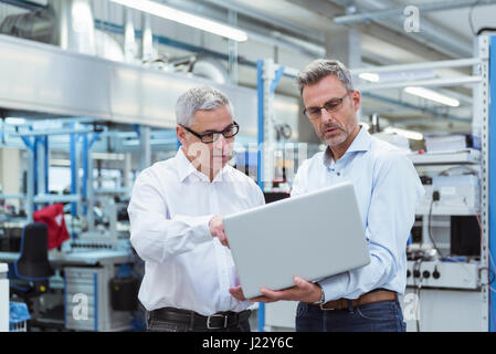 Zwei Manager in Unternehmen mit Laptop Stand Stockfoto