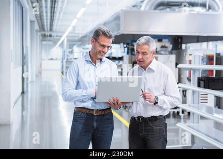 Zwei Manager in Unternehmen mit Laptop Stand Stockfoto