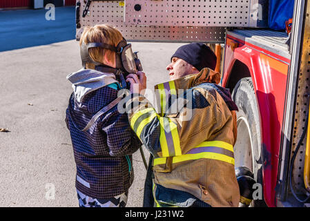 Hoby Brakne, Schweden - 22. April 2017: Dokumentation der öffentlichen Feuer LKW Präsentation. Feuerwehrmann helfende junge versuchen ein umluftunabhängiges appa Stockfoto